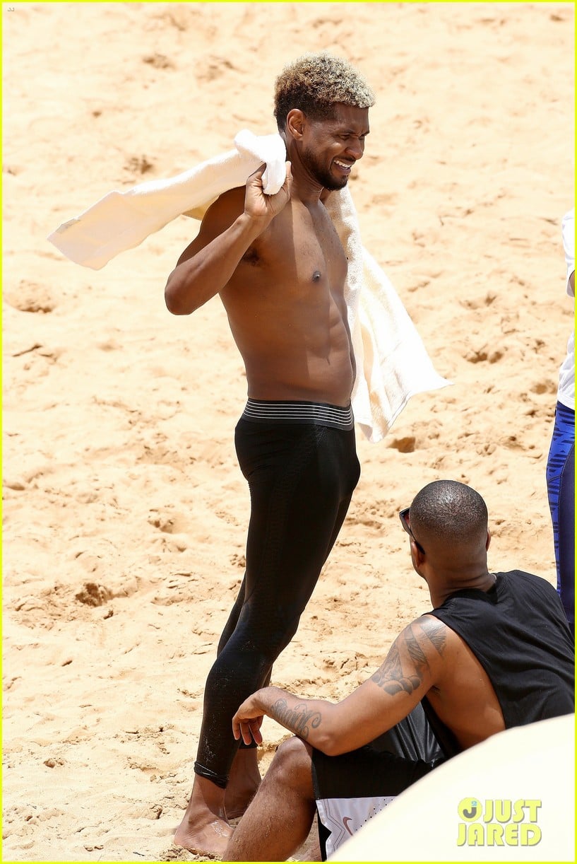 usher stays clothed while paddle boarding goes shirtless on beach 10