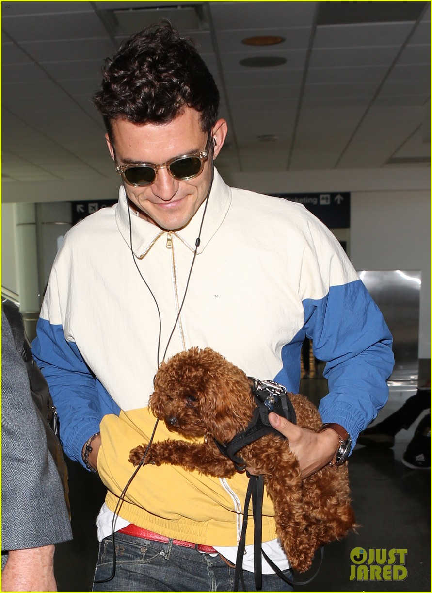 orlando bloom carries his cute dog through the airport 093915470